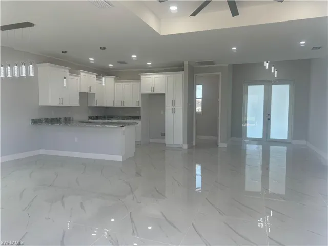 Kitchen featuring french doors, white cabinets, light tile flooring, and pendant lighting