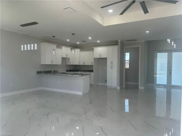 Kitchen featuring light tile flooring, hanging light fixtures, ceiling fan, white cabinetry, and french doors