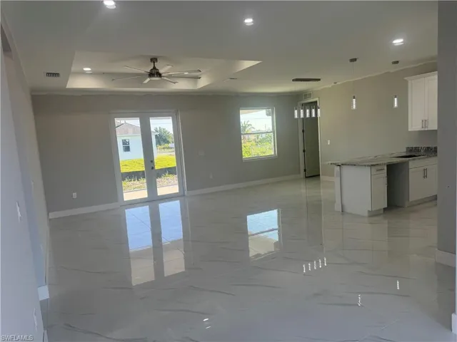 Kitchen with plenty of natural light, a tray ceiling, white cabinets, and light tile floors
