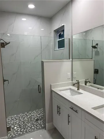 Bathroom featuring a shower with door, tile flooring, and dual bowl vanity