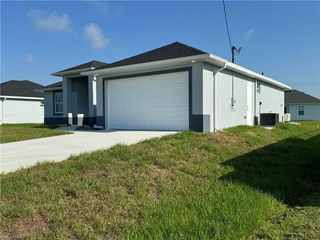 View of property exterior with a garage, central AC, and a lawn