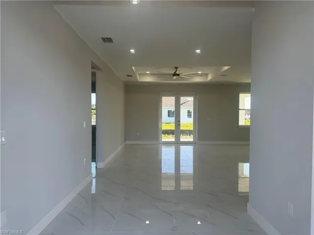 Unfurnished room with tile flooring, ceiling fan, a raised ceiling, and french doors