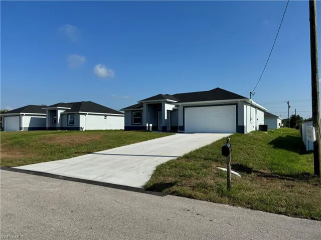 View of front facade featuring a garage and a front lawn