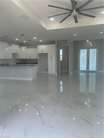 Unfurnished living room featuring ceiling fan, french doors, and light tile floors