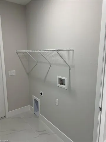 Clothes washing area with tile flooring, washer hookup, and hookup for an electric dryer