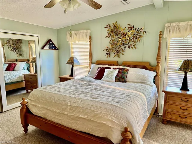 Carpeted bedroom featuring lofted ceiling with beams.