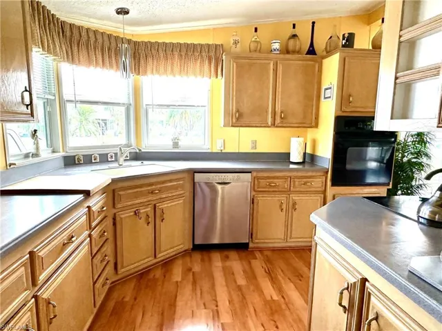 Kitchen featuring corin countertops,oven, glass stove top, dishwasher and refrigerator with icemaker. Light hardwood / wood-style flooring.