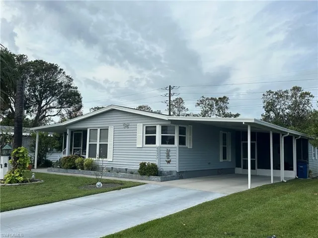 View of front of property featuring a front lawn, central AC unit, and a carport