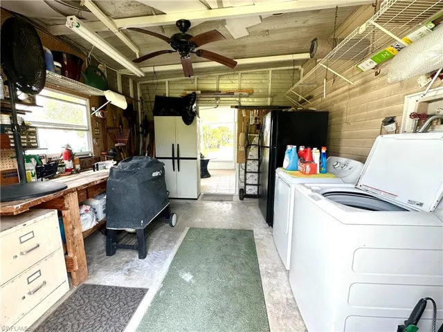 Clothes washing area featuring washing machine and dryer, a workshop area, and ceiling fan