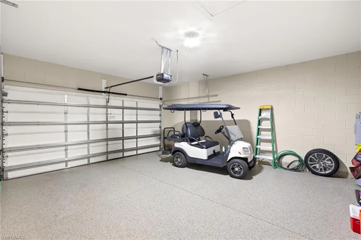 Garage featuring a garage door opener and concrete block wall