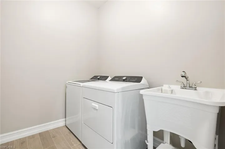 Washroom featuring independent washer and dryer and baseboards