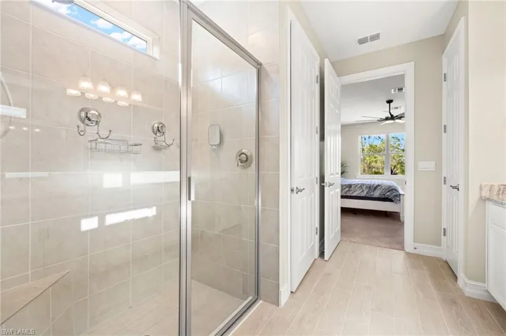 Ensuite bathroom featuring a shower stall, vanity, and ceiling fan