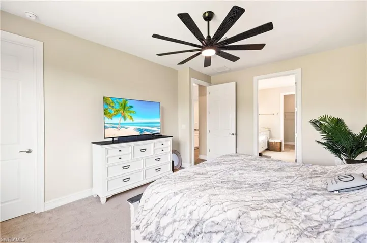 Bedroom featuring light colored carpet, connected bathroom, and a ceiling fan
