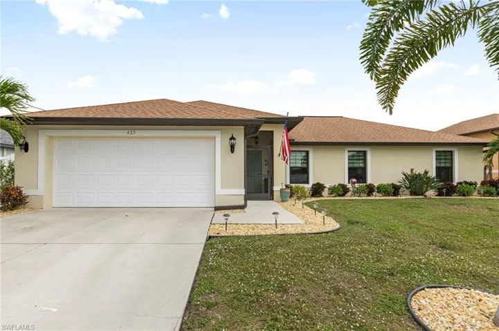 Ranch-style home featuring a shingled roof, stucco siding, a front lawn, and concrete driveway