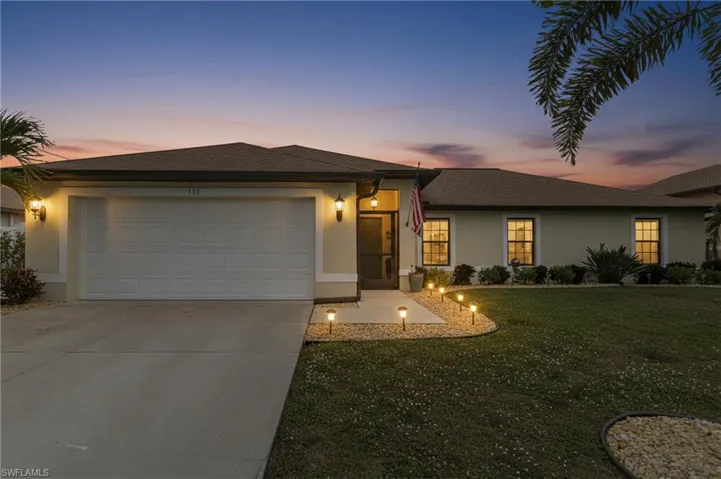 View of front of house featuring a front lawn, driveway, stucco siding, an attached garage, and roof with shingles