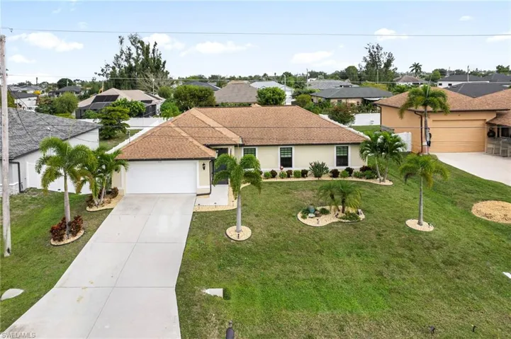Ranch-style home featuring driveway, stucco siding, an attached garage, a residential view, and a front lawn