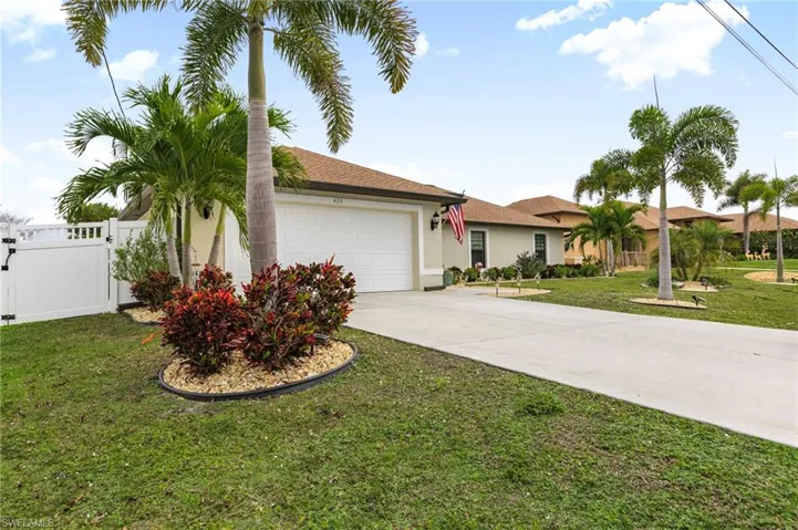 Ranch-style house with driveway, an attached garage, stucco siding, and a gate