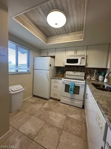Kitchen with stove, tasteful backsplash, fridge, and a raised ceiling