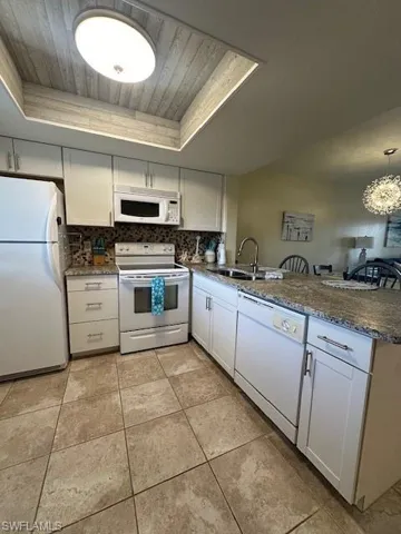 Kitchen featuring refrigerator, dishwasher, stove, and a tray ceiling