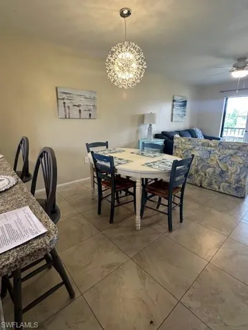 Tiled dining room with ceiling fan with notable chandelier