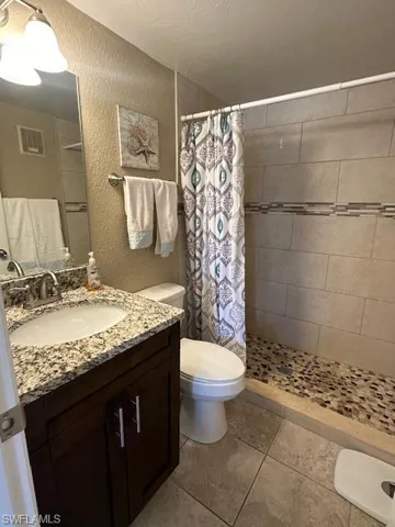 Master Bathroom with tile patterned floors, vanity, a shower with curtain, and toilet