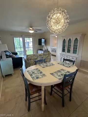 Dining room featuring ceiling fan with notable chandelier and light tile patterned floors