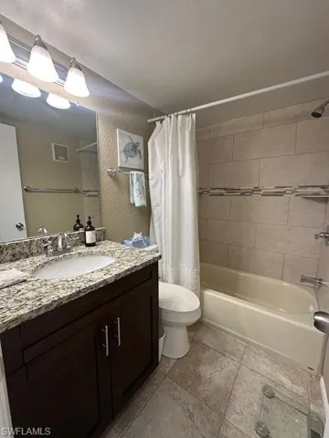 Full bathroom with vanity, shower / tub combo, tile patterned flooring, and toilet