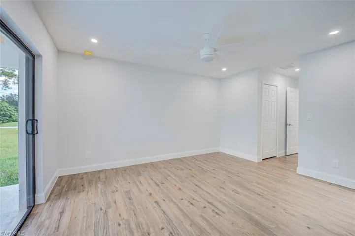 Wood-finish flooring, recessed lighting, ceiling fan, and sliding glass door