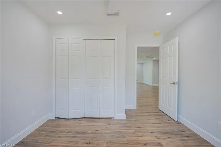 Room featuring wood-finish flooring, recessed lighting, and a bi-fold closet door
