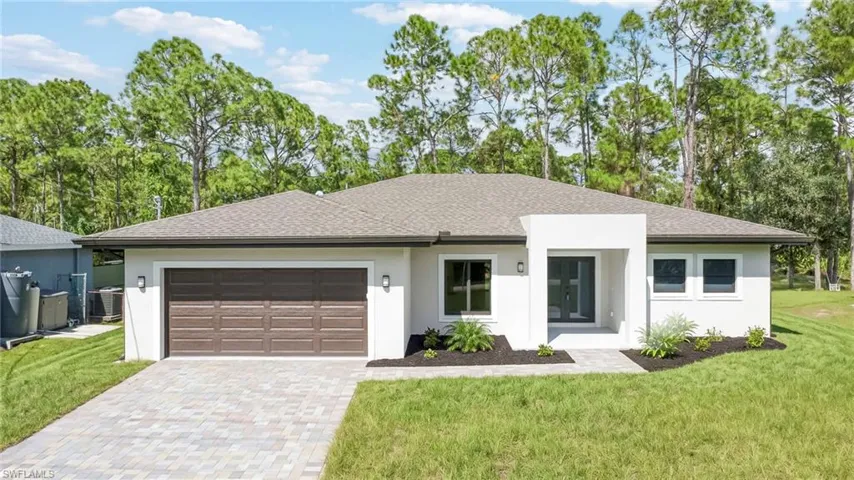 Single-story residence featuring a smooth stucco exterior, asphalt shingle roof, two-car garage with a panel door, and a paver driveway