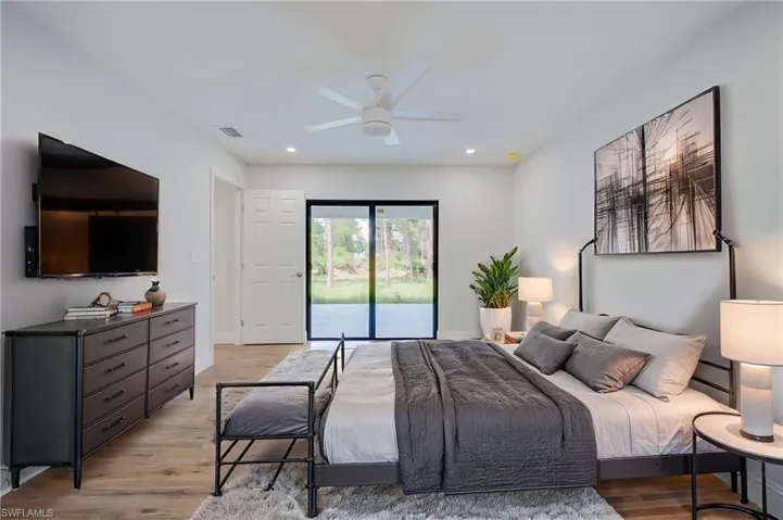 Wood-finish flooring, recessed lighting, ceiling fan, and black-framed sliding glass doors