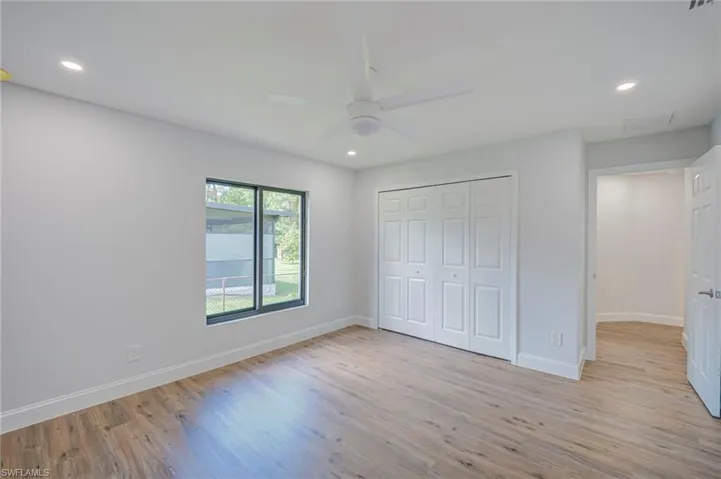 Neutral-toned room featuring wood-finish flooring, recessed lighting, a ceiling fan, and a multi-panel closet