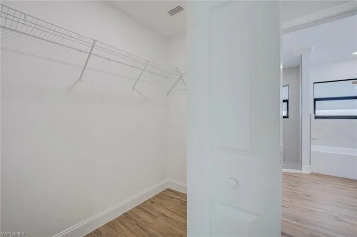 Walk-in closet featuring white wire shelving and wood-finish flooring