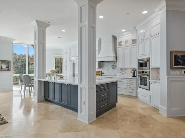 Kitchen featuring premium range hood, stainless steel built in fridge, crown molding, ornate columns, and white cabinetry