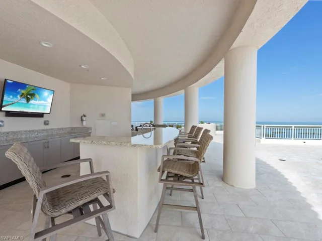 View of patio / terrace with a water view, exterior bar, and a view of the beach