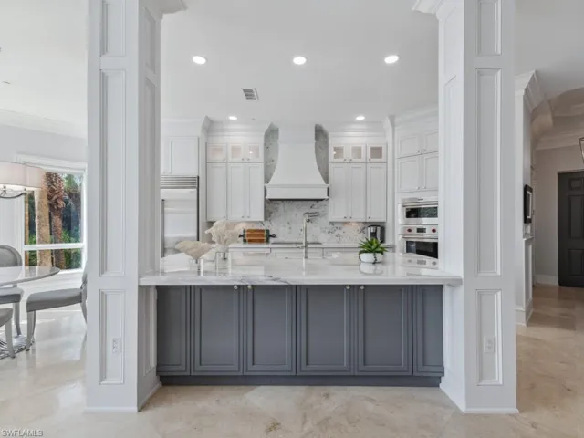 Kitchen with premium range hood, crown molding, white cabinets, and stainless steel built in refrigerator