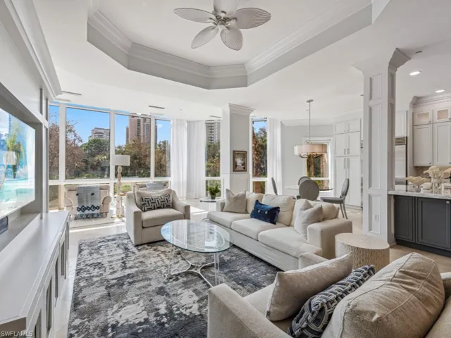 Living room with a tray ceiling, ceiling fan, ornamental molding, and decorative columns