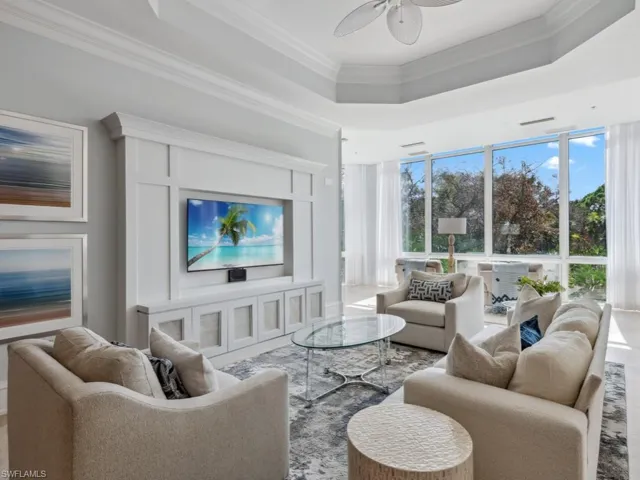 Living room featuring a tray ceiling, ceiling fan, and ornamental molding