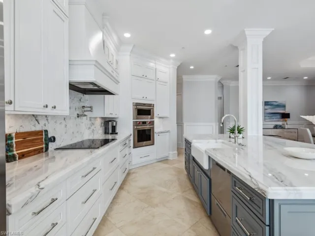 Kitchen featuring ornate columns, white cabinetry, black electric stovetop, and custom exhaust hood