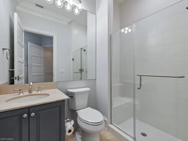 Bathroom featuring vanity, toilet, walk in shower, and ornamental molding