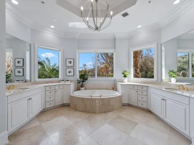 Bathroom with tiled tub, crown molding, vanity, and a healthy amount of sunlight