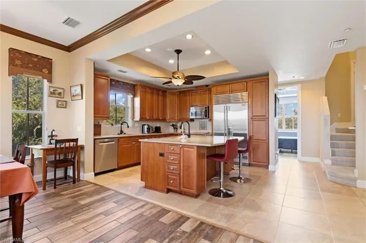 Kitchen featuring brown cabinets, a breakfast bar, an island with sink, stainless steel appliances, and recessed lighting