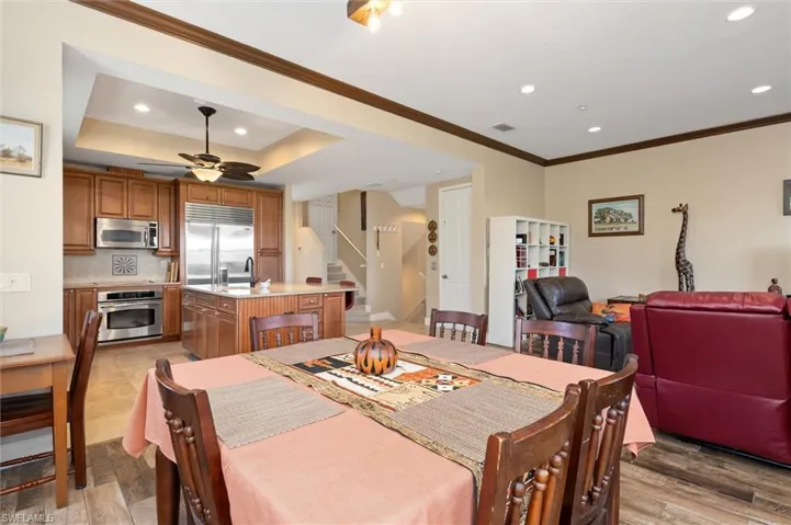 Dining area featuring stairs, recessed lighting, a ceiling fan, crown molding, and a tray ceiling
