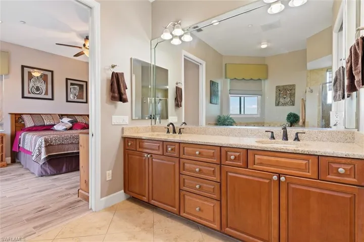 Ensuite bathroom featuring double vanity, ceiling fan, and an enclosed shower