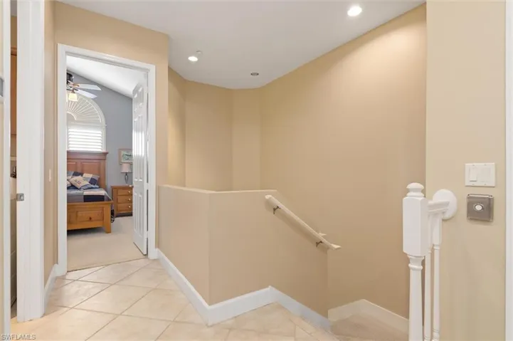 Hall with an upstairs landing, light tile patterned flooring, and recessed lighting
