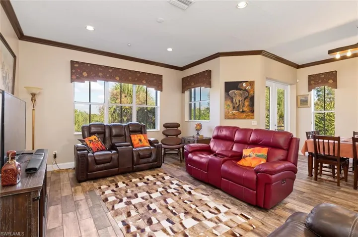 Living room featuring light wood-style flooring, ornamental molding, plenty of natural light, and recessed lighting