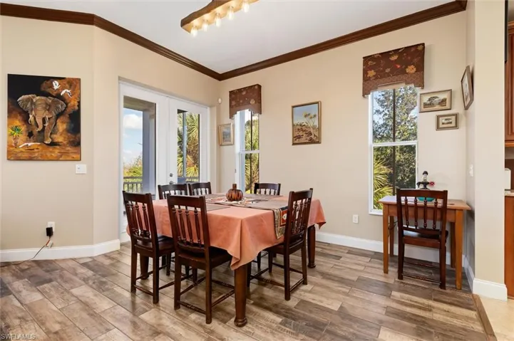Dining area featuring french doors, plenty of natural light, light wood-style floors, and ornamental molding