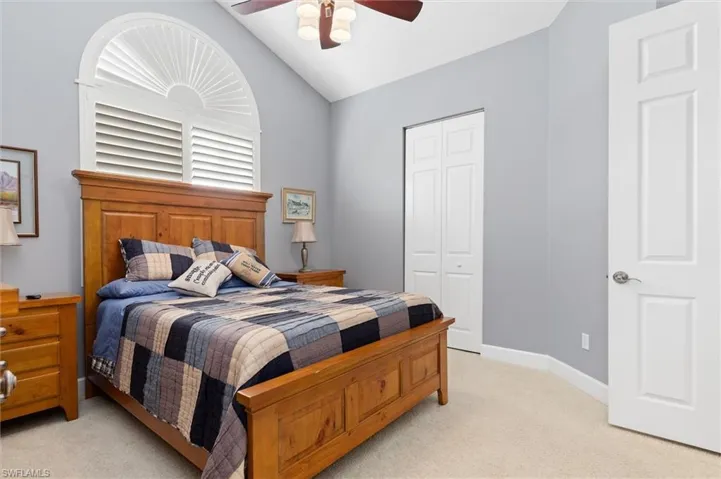 Bedroom featuring vaulted ceiling, light carpet, ceiling fan, and a closet