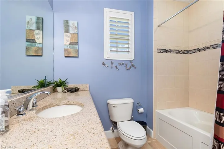 Bathroom with vanity, shower / tub combo, and tile patterned floors