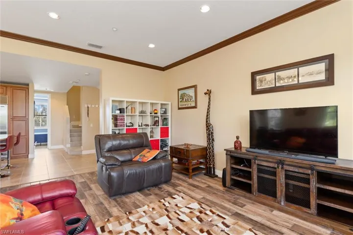 Living room featuring stairs, crown molding, light wood finished floors, and recessed lighting